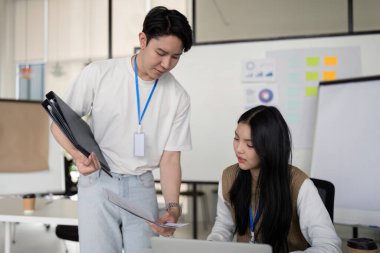 Bir erkek ve bir kadın, modern ofis ortamında etkili iletişim ve takım çalışması sergileyen finansal belgeler üzerinde işbirliği yapıyorlar..