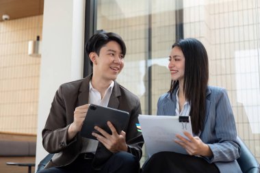 Proje materyallerini inceleyen, takım çalışması ve işbirliği sergileyen bir kadın ve erkek arasında yakın bir etkileşim..