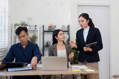 Çeşitli bir ekip, takım çalışmalarını ve etkili iletişimi vurgulayarak, parlak bir ofiste iş birliği yapar ve fikirleri paylaşır..