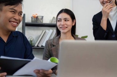 Neşeli bir ekip toplantı sırasında fikirleri ve kahkahaları paylaşıyor, modern bir ofiste olumlu bir çalışma ortamı yaratıyor..