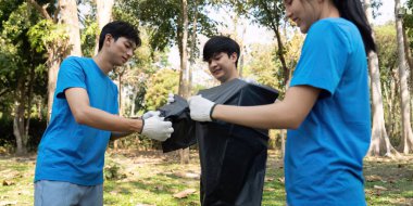 Genç gönüllülerden oluşan bir ekip, atık toplama, takım çalışması ve çevrenin korunmasına olan bağlılığı vurgulamak için işbirliği yapıyor..