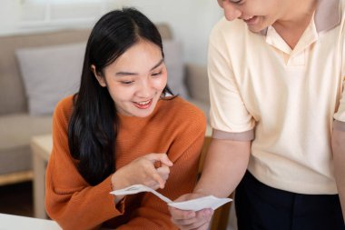 Bir çift aktif olarak hesaplarını planlıyor, makbuzları gözden geçiriyor ve bütçelerini yönetmek için hesap makinesi kullanıyor. Odaklanmış ve tartışmayla meşgul görünüyorlar..