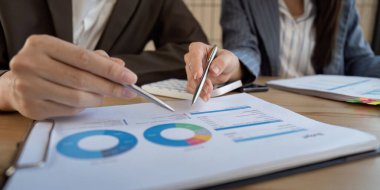 Etkili bir strateji oluşturmak için iki profesyonelin grafik ve mali raporları kullandığı odaklanmış bir iş birliği oturumu.