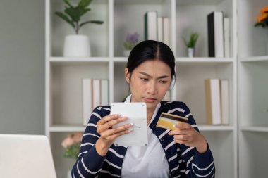 Bir kadın kredi kartı bilgilerini ve mali dökümanlarını kontrol ederken endişeli görünüyor..