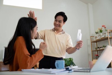 Genç bir çift finansal planlarında küçük bir zaferi kutluyor. Neşeli ifadeleri, mali durumları üzerinde birlikte çalışmanın olumlu yönlerini yansıtıyor.