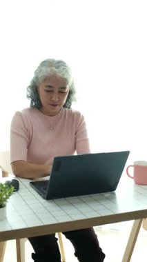 Yaşlı bir kadın dizüstü bilgisayar kullanıyor, öğrenme teknolojisinin yaş sınırı olmadığını gösteriyor. İnternette gezinmek, aileleri aramak ya da yeni bir şeyler öğrenmek, yaşlıların hoşuna gidebilir.