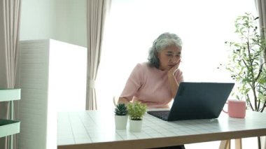 Yaşlı bir kadın dizüstü bilgisayar kullanıyor, öğrenme teknolojisinin yaş sınırı olmadığını gösteriyor. İnternette gezinmek, aileleri aramak ya da yeni bir şeyler öğrenmek, yaşlıların hoşuna gidebilir.