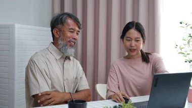 Torunu, yaşlı amcasına haber vermek için dizüstü bilgisayarı nasıl kullanacağını öğretiyor, oturma odasında nesiller arası öğrenme ve teknolojik evlat edinmeyi gösteriyor..