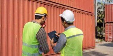 Mühendisler lojistik planlaması yapıyor, bir nakliye konteynırındaki çabalarını koordine etmek için tabletleri ve planları kullanıyorlar..