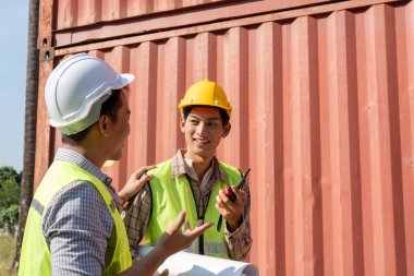 İki mühendis aynı fikirleri paylaşıyor ve lojistik stratejileri tartışıyor, konteyner ortamında takım çalışması sergiliyorlar..