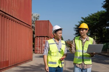 İki mühendis, modern planlama tekniklerini vurgulayarak bir dizüstü bilgisayar kullanırken lojistik hakkında stratejik bir tartışmaya giriştiler..