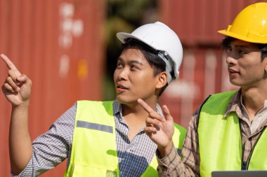 Güvenlik miğferli iki mühendis açık havada lojistik hakkında stratejik bir tartışmaya giriştiler..