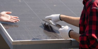 Bir teknisyen güneş panellerini inceleyerek yenilenebilir enerji çözümlerinde kalite ve bakıma olan bağlılığını ve verimliliği artırmak için teknolojiyi gösteriyor..