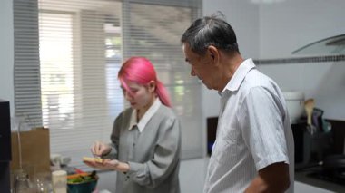 Büyükbaba ve torun birlikte mutfakta kaliteli zaman geçiriyorlar, neşe ve takım çalışması ile atıştırmalık hazırlıyorlar..