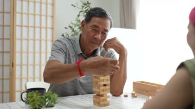 Büyükbaba ve torun birlikte ahşap bir oyun oynayarak hafta sonunun tadını çıkarıyorlar. Eğlenceyi, kahkahayı ve kaliteli zamanı paylaşıyorlar..