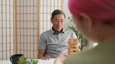 Büyükbaba ve torun birlikte ahşap bir oyun oynayarak hafta sonunun tadını çıkarıyorlar. Eğlenceyi, kahkahayı ve kaliteli zamanı paylaşıyorlar..