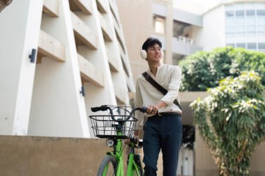 Bisikletin yanında yürüyüp müzik dinleyen bu şehir sakini, sürdürülebilir ulaşım ve kentsel hareketliliğe neşeli bir yaklaşımı yansıtıyor..