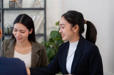 Çağdaş bir ofiste, iki kadın bir iş stratejisi üzerinde işbirliği yapar, masadaki belgeleri incelerken içgörü ve deneyimlerini paylaşırlar..