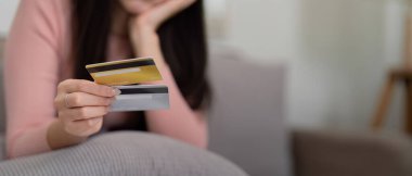 Seçimlerine odaklanan kadın, en iyi ödeme stratejisini belirlemek için kredi kartlarını düşünceli bir şekilde tartıyor..