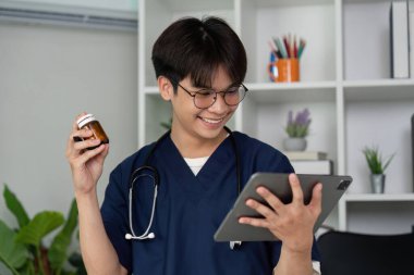 Tıp öğrencisi ilaç tedavisi anlayışlarını geliştirmek için ilaç bilgilerini araştıran bir tabletle neşe içinde ilgilenir..