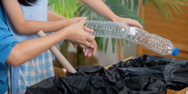 Eğitimsel bir aktiviteye katılan ve geri dönüşüme odaklanan küçük bir kız, annesinden oturma odasındaki atık yönetiminin sorumluluğunu öğreniyor..