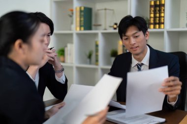 Odaklanmış bir grup avukat, dava hazırlıklarını geliştirmek için gerekli içgörüleri ve stratejileri tartışarak kritik yasal belgeleri inceliyor..