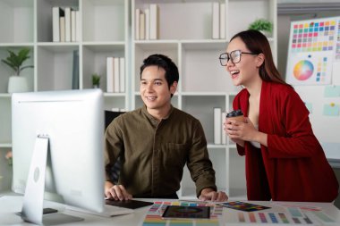 Takım üyeleri bir monitörde gösterilen tasarımlara hayran kalarak grafik tasarımında başarılı bir işbirliğinin altını çizerek neşeli bir değişim meydana gelir..