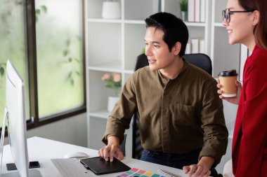 Tasarımcılardan oluşan bir ekip bir çalışma istasyonunun etrafında toplanarak renk seçeneklerini ve yenilikçi fikirleri araştırıyor. İşbirliği, projeleri içinde yaratıcılığı teşvik ediyor..