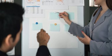 Bir kadın, meslektaşı işbirliği stratejileri sergileyerek not alırken veri analizinin kritik yönlerine işaret eder..