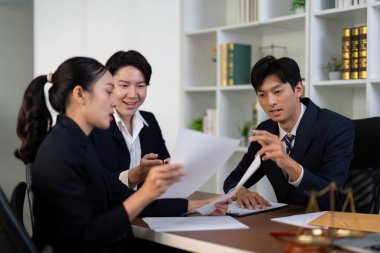 Bir grup avukat birlikte önemli belgeleri gözden geçirir, stratejileri tartışır ve profesyonel bir ofis ortamında davalarının iç görülerini paylaşırlar..