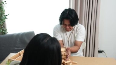 İki Asyalı genç arkadaş, bir erkek ve bir kız, okul molasında birlikte ahşap oyunlar oynayarak eğleniyorlar, kahkaha ve bağlanma anlarını paylaşıyorlar..