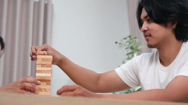 İki Asyalı genç arkadaş, bir erkek ve bir kız, okul molasında birlikte ahşap oyunlar oynayarak eğleniyorlar, kahkaha ve bağlanma anlarını paylaşıyorlar..