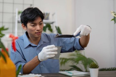 Bitki ortamını yeniden şekillendirmeye odaklanan bu adam, yeniden saksı dikme sırasında büyüme koşullarını iyileştirmek için bir mala kullanıyor..