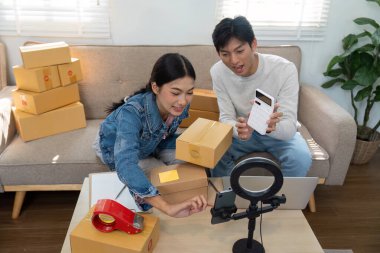 İki girişimci e-ticaret siparişlerini verimli bir şekilde yönetiyor. Ürünleri paketleyip eve teslim etmeye hazırlanırken takım çalışması sergiliyorlar..