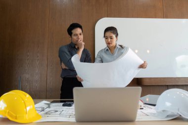 Meslektaşlar, tasarım analizi ve proje hazırlıklarında işbirliği göstererek, mimari planları birlikte inceler..