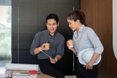 Etkileşimli bir oturumda, mühendisler çalışma süreçleri boyunca işbirliğini ve etkili iletişimi vurgulayan bir tablet üzerindeki proje ayrıntılarını gözden geçirirler..