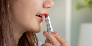 Kusursuz bir hareketle, dudaklarında kırmızı ruj süzülür, kendine güvenle büyüleyici bakışını tamamlar..