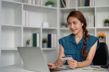 Kadın çevrimiçi alışveriş yaparken dijital dünyadaki modern finansal yönetimi gösteren kredi kartını kullanırken gülümsüyor..