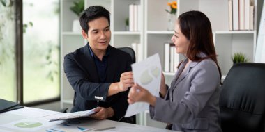 Bir toplantı sırasında iki profesyonel, mali verileri anlamada ve analiz etmede işbirliğini güçlendirerek rapor alışverişinde bulundu.