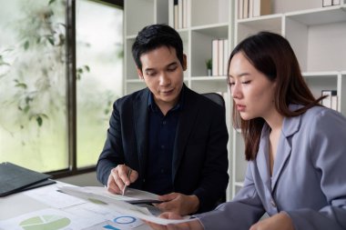 Profesyonel bir çift, analitik raporları grafikler ve grafiklerle gözden geçirir, modern ofis atmosferinde karar verme süreçlerindeki takım çalışmalarını gösterir.
