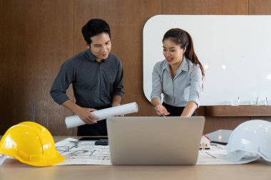 İki meslektaş, planlarını incelerken, mühendislik ortamında takım çalışması ve stratejik planlama sergilerken verimli bir tartışmaya giriştiler..