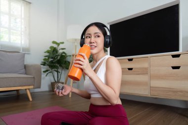 Bir fitness meraklısı, müzik dinlerken içkisinin tadını çıkararak egzersiz ve rahatlama dengesini örnek alıyor..