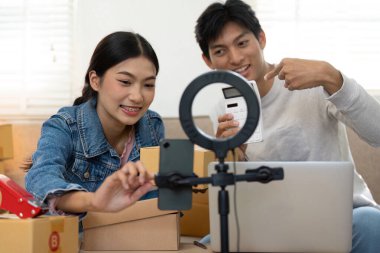 Bir çift, bir online mağaza için iş stratejilerini tartışırken, girişimci ruhlarını gözler önüne sererek ve dijital varlıklarını göstererek bir video kaydediyor..