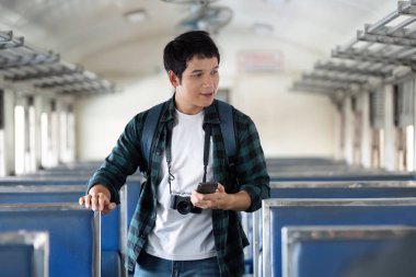 Sessiz bir tren vagonunda, genç bir adam elinde kamerayla duruyor, telefonuyla bir sonraki macerasını planlıyor, seyahatinin huzurunu yaşıyor..