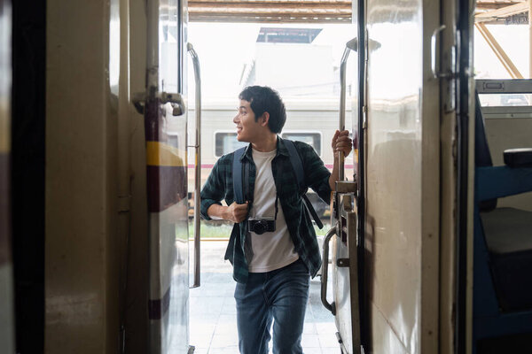 A young man opens the train door and steps inside, looking back with a joyful expression. His camera signifies that he is ready to capture moments during his adventure.