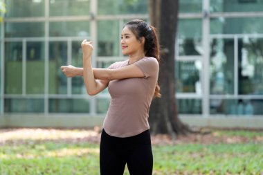 Sakin bir açık hava ortamında, bir kadın odaklanmış kol esnemeleri, esnekliği ve genel olarak sağlıklılığı ile spor yolculuğuna devam eder..