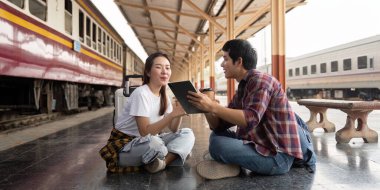 Hareketli bir tren istasyonunda, bir çift yerde oturup yaklaşan seyahatleri hakkında tartışırlar. İlerideki yolculuklarının heyecanı parlıyor.