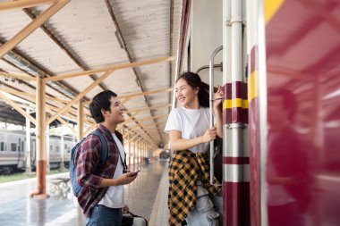 Çift, yolculuklarına hazırlanmak için tren vagonunda neşeli bir anı paylaşıyor. Gülümsemeleri, yolculuklarının mutluluğunu ve beklentilerini yansıtıyor..