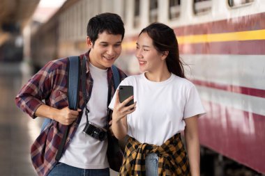 Mutlu bir çift tren istasyonunda bekliyor, birlikte telefonlarına bakıyorlar, yaklaşan yolculuklarını hevesle tartışıyorlar. Atmosfer macera ve heyecanla dolu..
