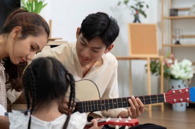 Küçük bir kızın gitar derslerinin keyfini çıkarırken anne ve babasının cesaret verdiği ve müzik yaptığı bir aile müzik seansı..